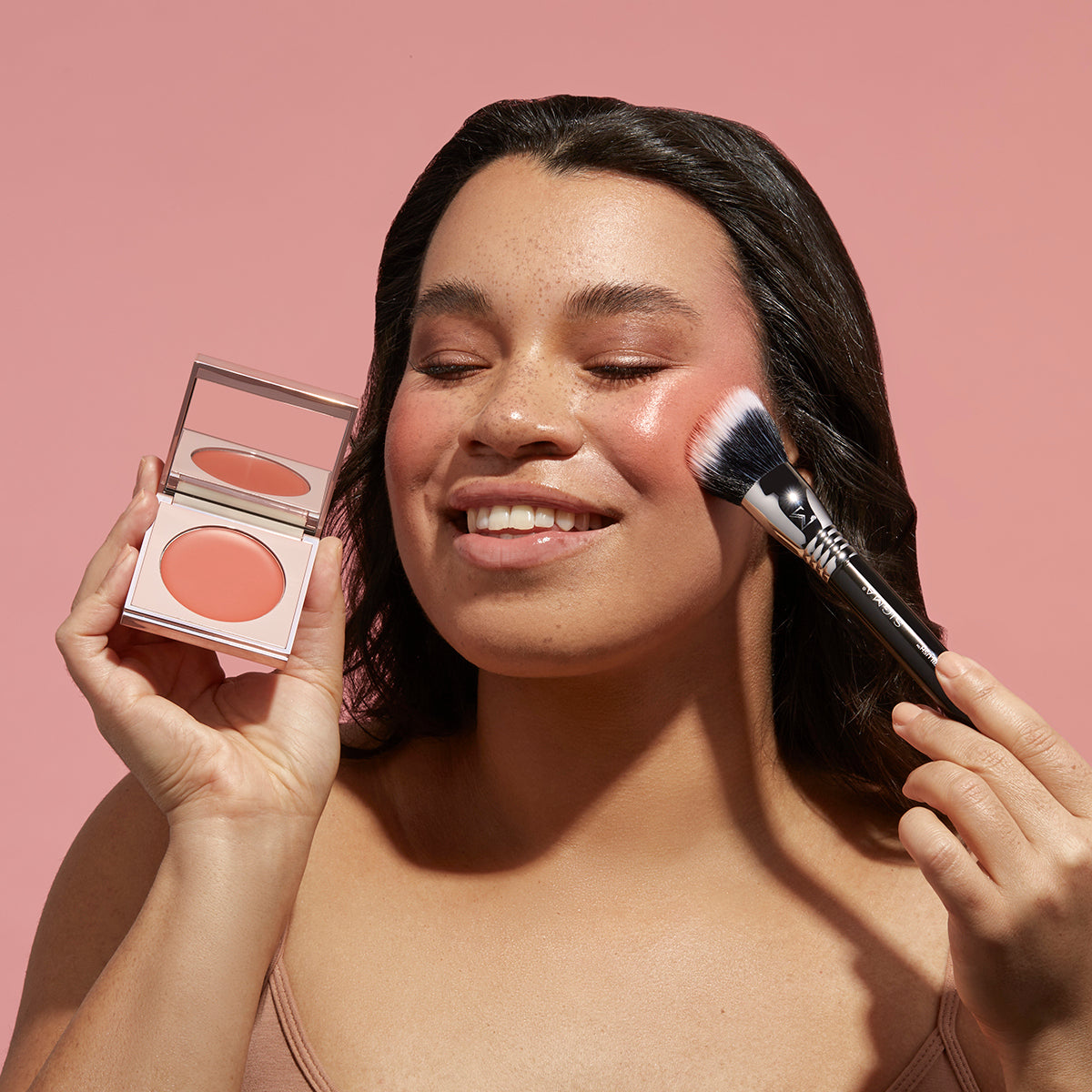 Model applying Sigma Beauty Cream Blush 